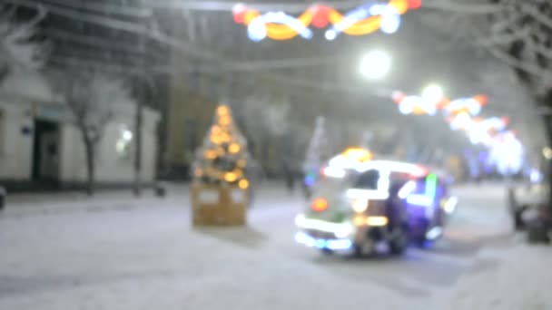 Размытый фон снежной городской улицы с елками и подсветкой — стоковое видео