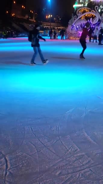 Mensen schaatsen op een ijsbaan met kleurrijk licht — Stockvideo