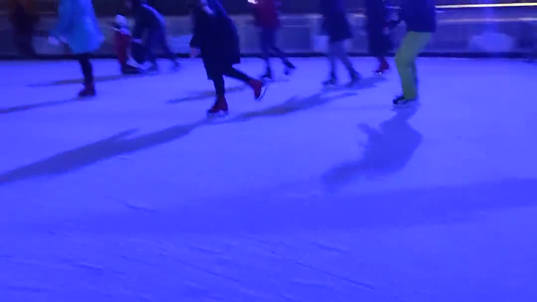 Persone che pattinano su una pista di pattinaggio su ghiaccio con luce colorata all'aria aperta in inverno — Video Stock