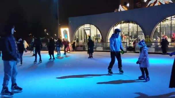Människor skridskor på en skridskobana med färgglada ljus i det fria — Stockvideo