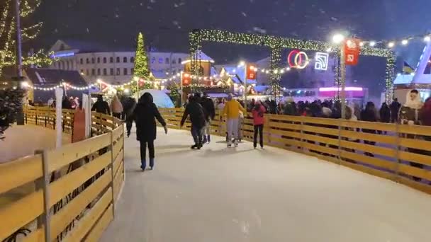Muchas personas están patinando sobre hielo al aire libre pista de patinaje nevada — Vídeos de Stock