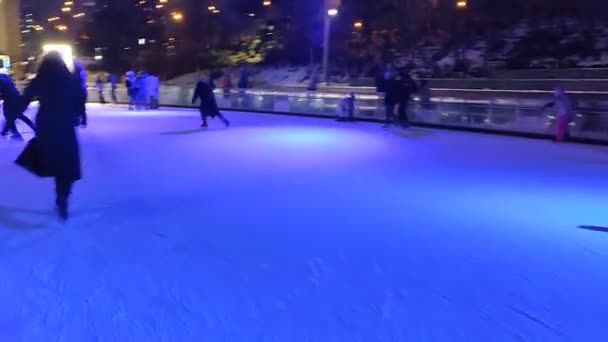 Pessoas patinando em uma pista de patinação no gelo com luz colorida ao ar livre — Vídeo de Stock