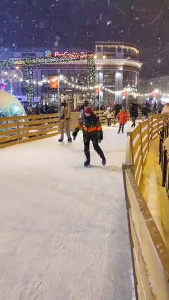 Birçok insan açık havada buz pateni pistinde paten kayıyor. Dikey video — Stok video