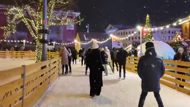 Molte persone stanno pattinando sulla pista di pattinaggio all'aperto nevicate — Video Stock