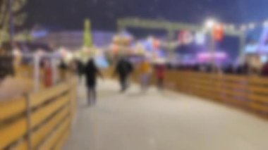 Arka plan bulanık. Birçok insan açık havada buz pateni pistinde kayıyor.