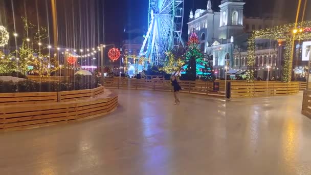 Girl skates and figure skating with ribbon on city open air ice rink on winter. — Stock Video