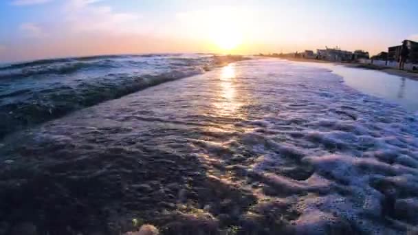 Muy bajo ángulo de tiro de olas de mar estrellándose en una playa de arena. — Vídeos de Stock