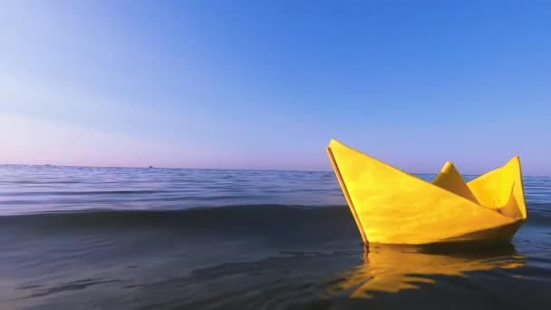 Žlutý papírový člun plave na hladině modré vody vlny moře zblízka. — Stock video