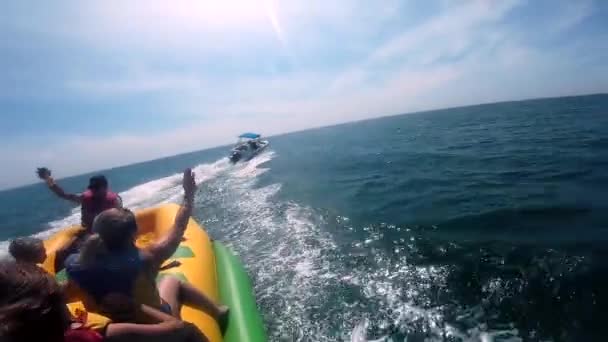 La gente que monta en la atracción inflable del agua con el barco a motor plátano en el mar — Vídeos de Stock