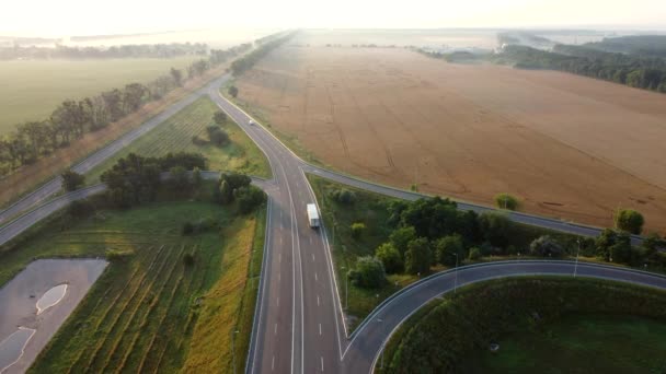 Полет беспилотника над автомобильной дорогой между сельскохозяйственными пшеничными полями — стоковое видео