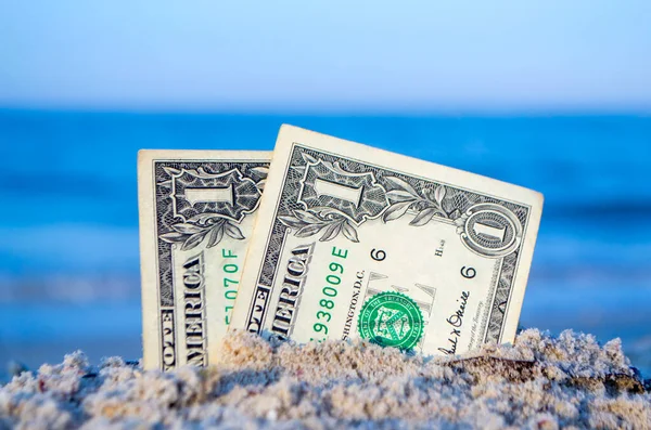Twee dollarbiljetten half begraven in zand aan de kust.. — Stockfoto
