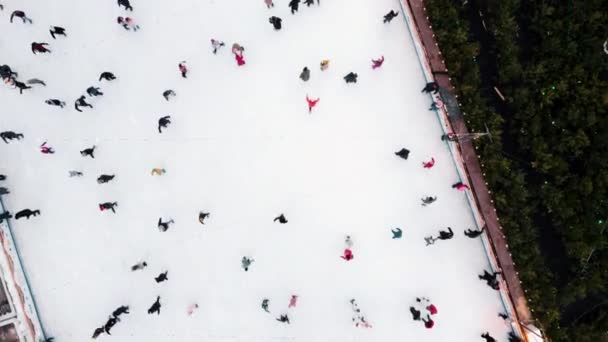 Vista aérea do drone sobre muitas pessoas patinando em uma pista de gelo ao ar livre no inverno. — Vídeo de Stock