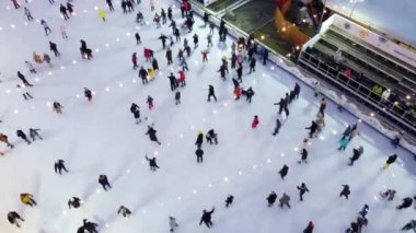 Kışın açık hava buz pateni pistinde paten kayan pek çok insan üzerinde hava aracı görüntüsü.