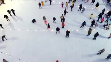 Kışın açık hava buz pateni pistinde paten kayan pek çok insan üzerinde hava aracı görüntüsü.