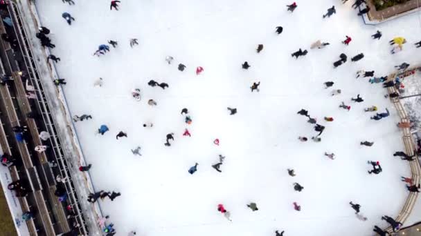 Drohnenblick über viele Menschen, die im Winter auf einer Eisbahn unter freiem Himmel Schlittschuh laufen. — Stockvideo
