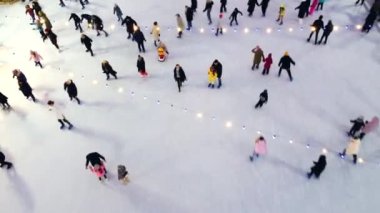 Kışın açık hava buz pateni pistinde paten kayan pek çok insan üzerinde hava aracı görüntüsü.