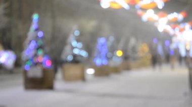 Arka plan bulanık. Kış gecesi kar yağarken şehir caddesi.