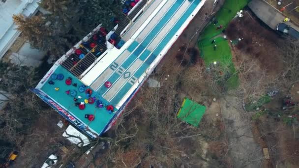 Kinderen rijden van de besneeuwde heuvel af. LuchtDrone View — Stockvideo