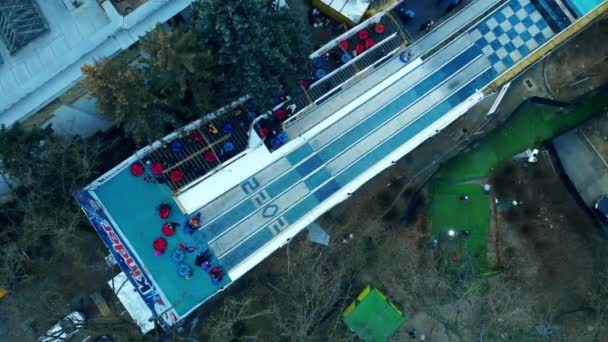 Kinderen rijden van de besneeuwde heuvel af. LuchtDrone View — Stockvideo