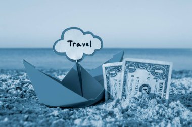 İki kağıt bir banknot. Yarısı kum ve turuncu kağıt tekneye gömülmüş.