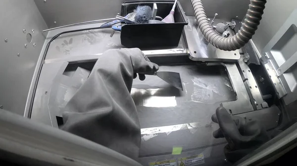 Mężczyzna pracownik w gumowej rękawicy czyści platformę drukarską wewnątrz drukarki 3d do metalu — Zdjęcie stockowe