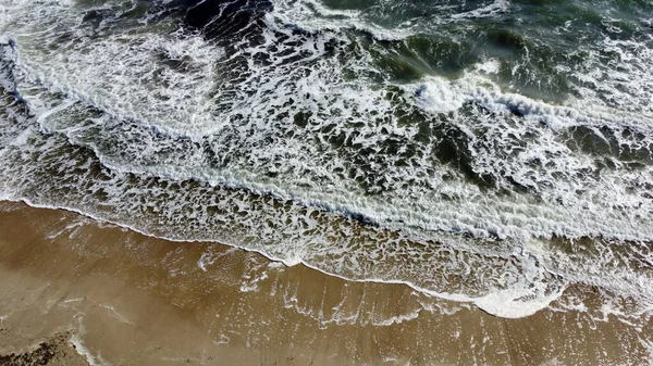 Avión teledirigido vuelo sobre las olas del mar que rodar sobre la orilla arenosa. —  Fotos de Stock