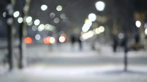 Vista de la ciudad luces, nieve cayendo, calle nocturna, bokeh manchas de faros de coches — Vídeo de stock