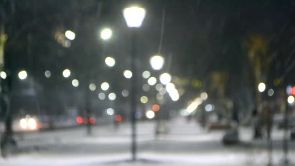 Vista de la ciudad luces, nieve cayendo, calle nocturna, bokeh manchas de faros de coches — Vídeo de stock