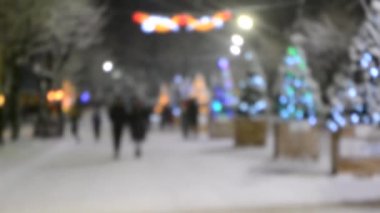 Arka plan bulanık. Kış gecesi kar yağarken şehir caddesi.