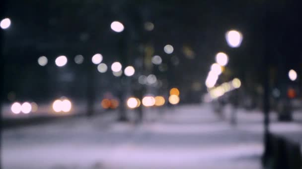 City view lichten, vallende sneeuw, nacht straat, bokeh vlekken van koplampen van auto 's — Stockvideo