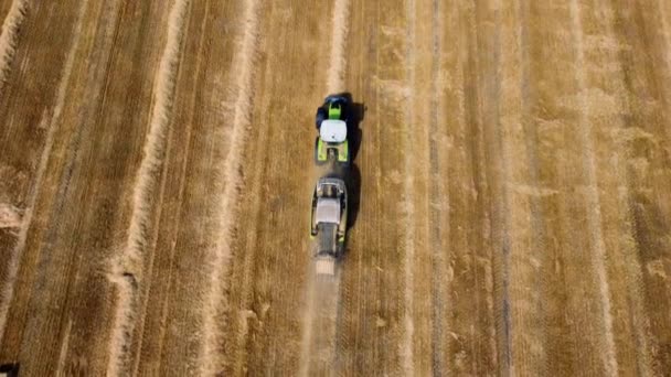 Серый тюк трактор. Трактор собирает сено в тюки в поле в солнечный день. — стоковое видео