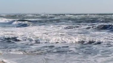 Fırtınalı deniz. Fırtınalı denizin dalgaları güneşli bir günde kıyıda yuvarlanıyor..