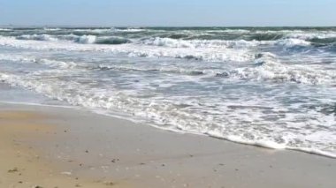 Fırtınalı deniz. Fırtınalı denizin dalgaları güneşli bir günde kıyıda yuvarlanıyor..
