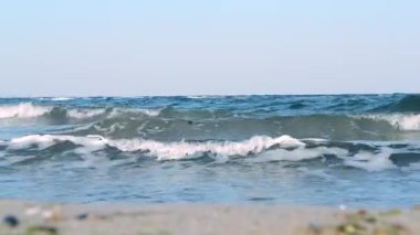 Fırtınalı deniz. Fırtınalı denizin dalgaları güneşli bir günde kıyıda yuvarlanıyor.