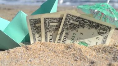 Yeşil küçük kağıt tekne, üç dolarlık banknotlar, kağıt kokteyl şemsiyesi.