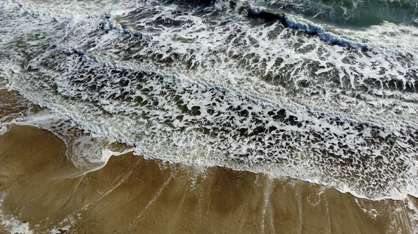 Vuelo aéreo con vista al dron sobre hermosas olas marinas en la playa de arena con espuma blanca —  Fotos de Stock