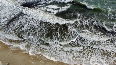 Kum sahilinde beyaz köpüklü güzel deniz dalgaları üzerinde uçan hava aracı görüntüsü