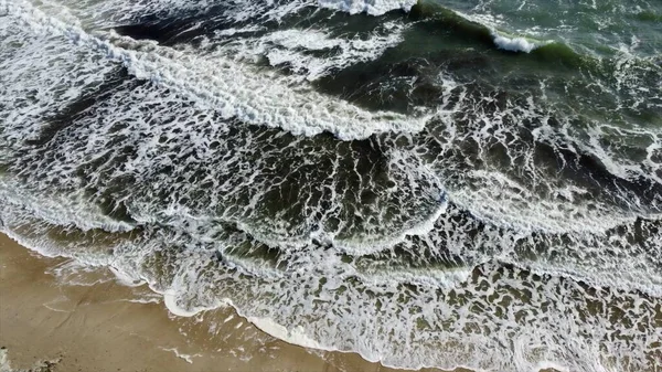 Kum sahilinde beyaz köpüklü güzel deniz dalgaları üzerinde uçan hava aracı görüntüsü