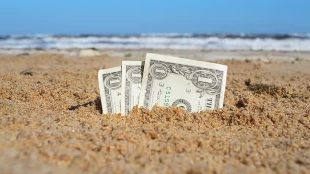 Paper bills one dollar buried in the sand on the beach against the backdrop — Vídeos de Stock