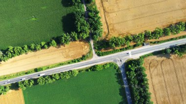 Tarımsal alanlar arasındaki asfalt yol kesişiminde hava aracı görüntüsü