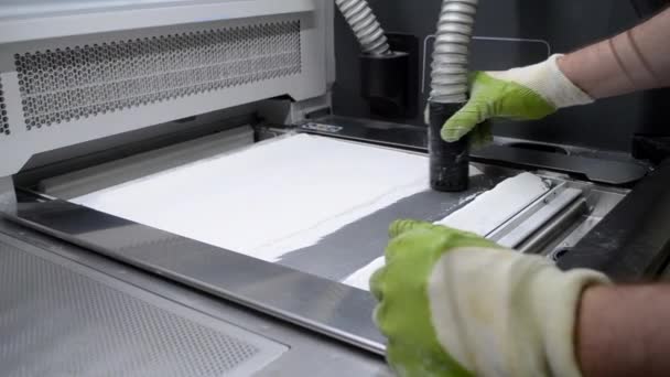 Egy férfi munkás megtisztítja az ipari 3D nyomtató felületét a fehér portól — Stock videók