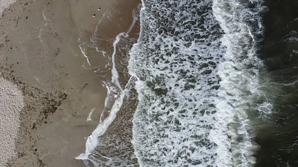 Kum sahilinde beyaz köpüklü güzel deniz dalgaları üzerinde uçan hava aracı görüntüsü