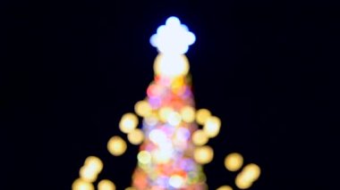 Büyük bir yılbaşı ağacı. Parlak renkli çelenkler ve gece aydınlatmasıyla süslenmiş. Yanıp sönen ışıkları olan Noel ağacı. Arka plan bulanık. Yılbaşı ve Noel tatili