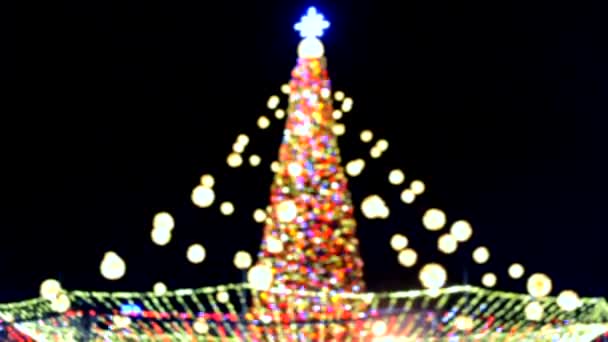 Großer Silvesterbaum geschmückt mit leuchtenden bunten Girlanden und nächtlicher Beleuchtung. Weihnachtsbaum mit Blaulicht. Unscharfer Hintergrund. Neujahr und Weihnachtsfeiertage