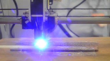 3D yazıcı lazer ışını bir ahşap tahta üzerine desen yakın çekim yakar. Endüstriyel Modern teknolojik arka plan. Mavi lazer 3d printerlere harcama maddeler ahşap yüzey yanıkları kelime üstünde hareket resimler