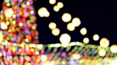 Büyük bir yılbaşı ağacı. Parlak renkli çelenkler ve gece aydınlatmasıyla süslenmiş. Yanıp sönen ışıkları olan Noel ağacı. Arka plan bulanık. Yılbaşı ve Noel tatili