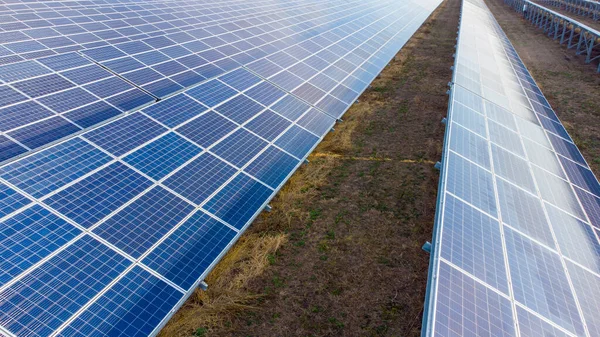 Aerial drone view flight over solar power station panels. Aerial top view of solar farm. Green energy, electrical innovation. Renewable Energy. Industrial Solar Energy Farm producing solar power.