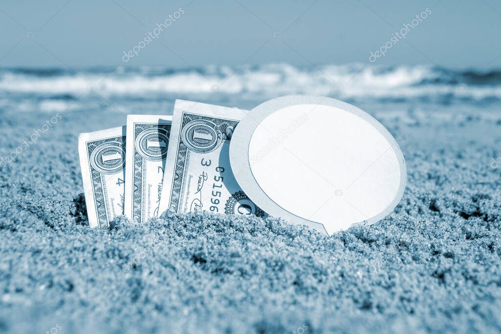 Paper bills one dollar, small stick clean empty paper speech bubble buried in sand beach background sea close-up in sunny summer day. Concept Money travel tourism vacation holiday. Blue white color
