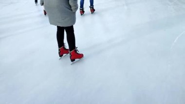 People skating on public open-air ice skating rink in city on winter day. People skating on ice rink. Legs, back, ice rink. Winter holidays, activities ,recreation ,rest, sport