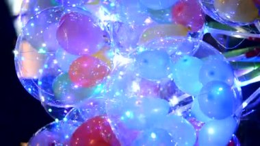 İçinde parlak çelenkler olan balonlar. Soyut renkli arkaplan. İçinde yanıp sönen çelenkler olan bir sürü renkli balon. Tatil, kutlama, yeni yıl, Noel. Dikey video